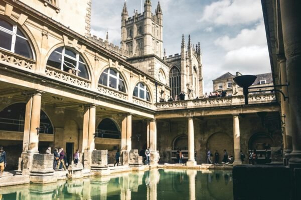 The Great Bath pool with surrounding galleries and Bath Abbey beyond