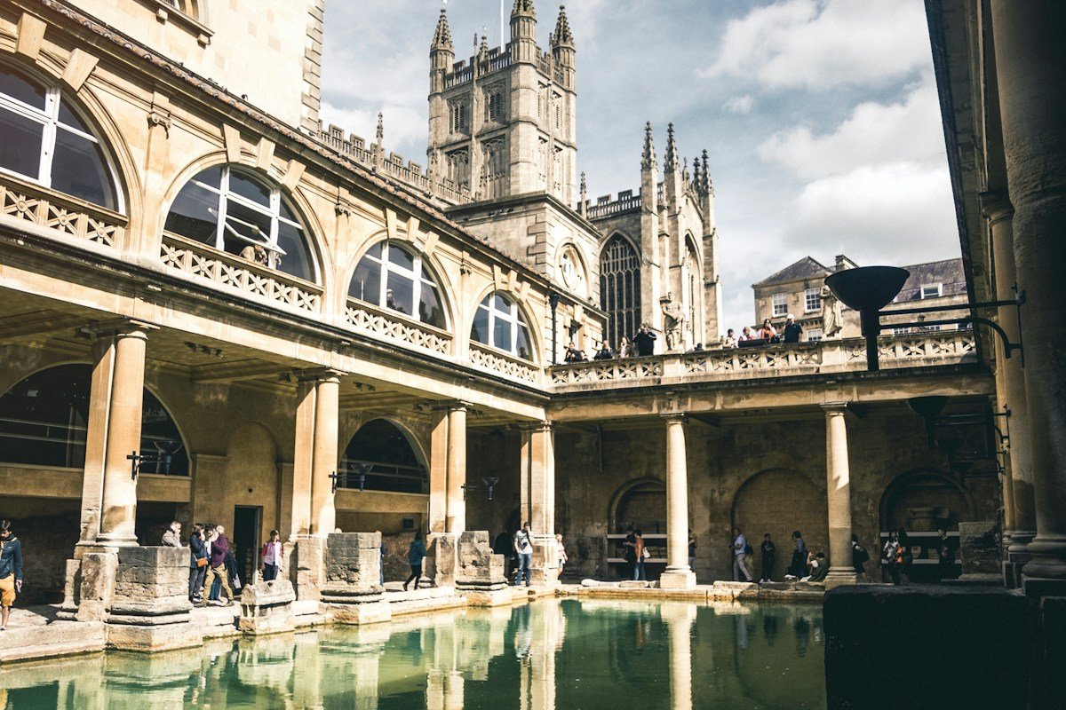 The Great Bath pool with surrounding galleries and Bath Abbey beyond